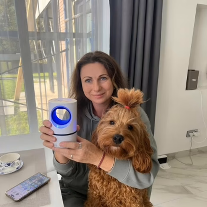 Owner holding the ZapiTrap lamp next to her dog in the living room